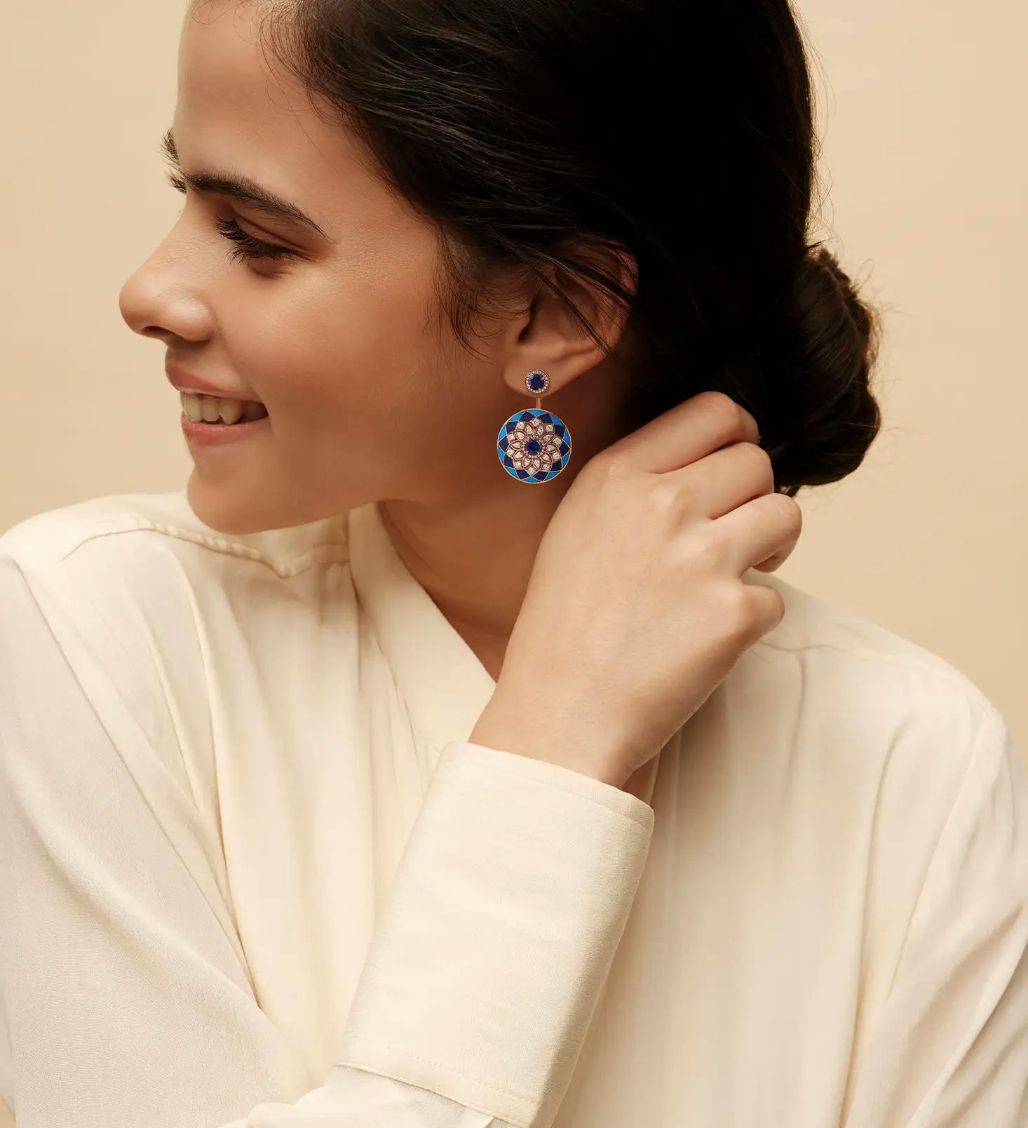 Woman wearing 18K recycled rose-gold earrings with lapis and turquoise inlay, pear and cushion-cut diamonds and iolites.